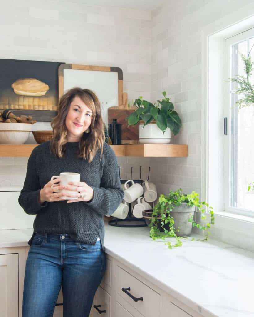 Woman in a kitchen with plants.