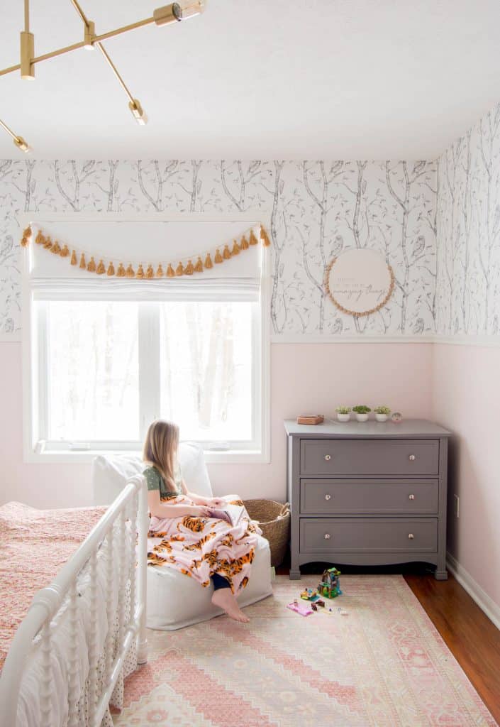 Little girl sitting in a pink room.