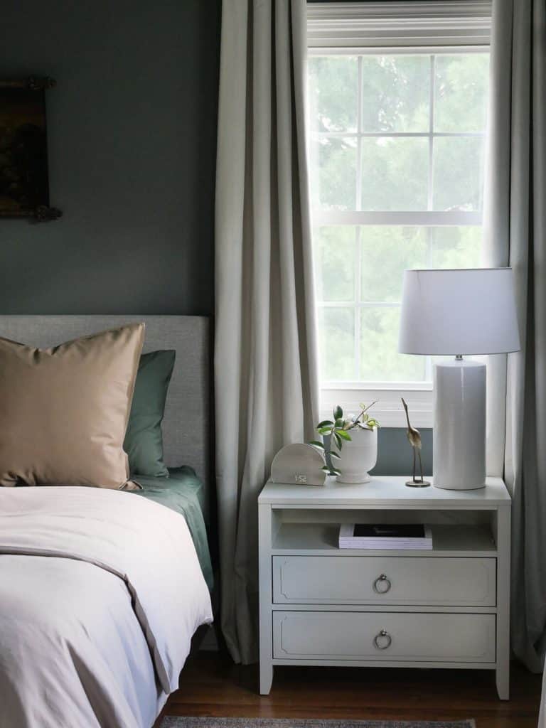 Primary bedroom with moody green walls and lighter accents.