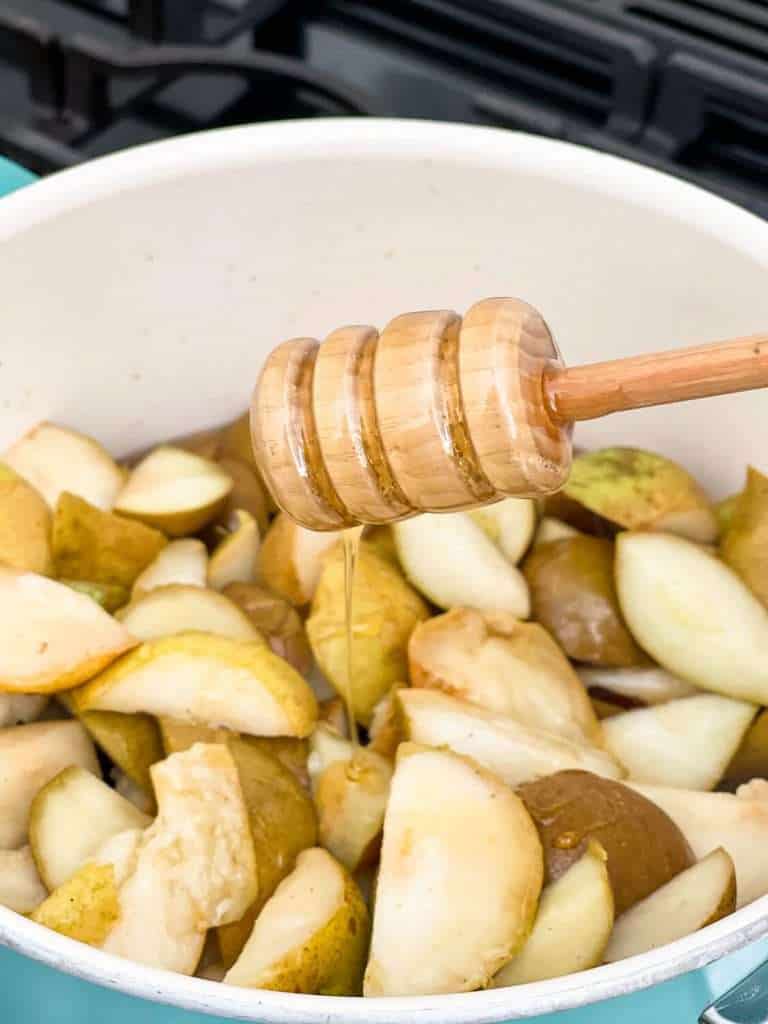 Adding honey to a pot of unripe pears.