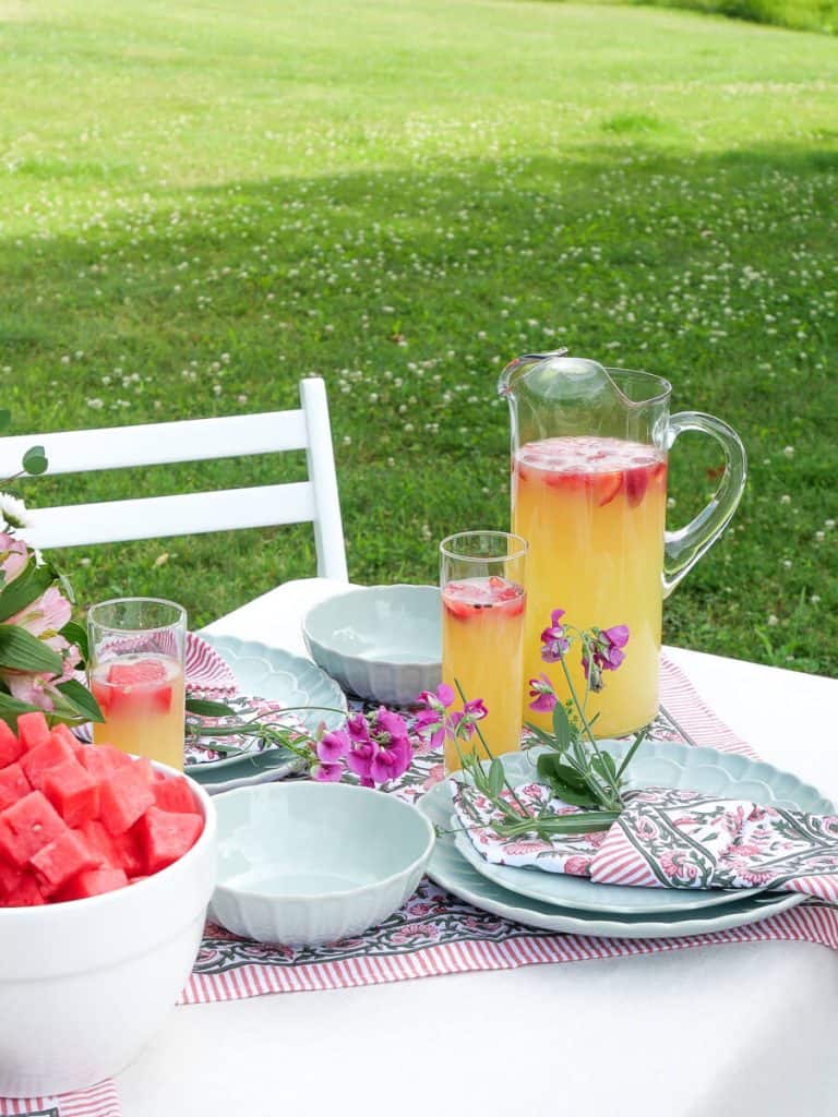 Pitcher of lemonade with dishes.