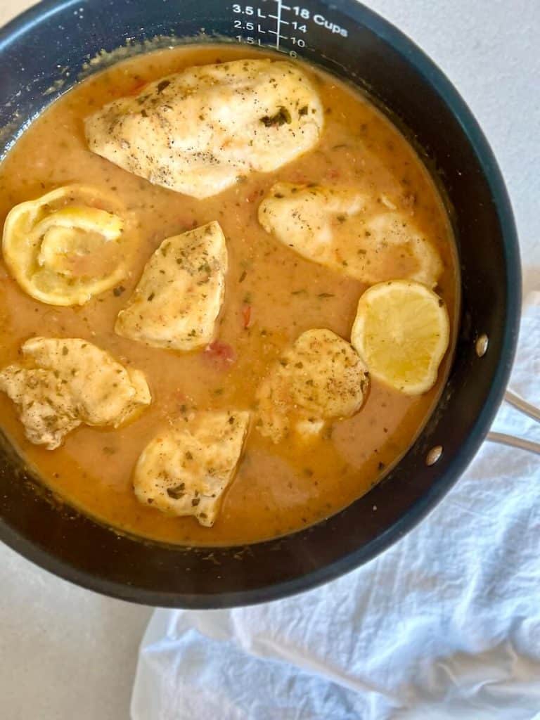 Lemon basil chicken with sauce in a skillet.