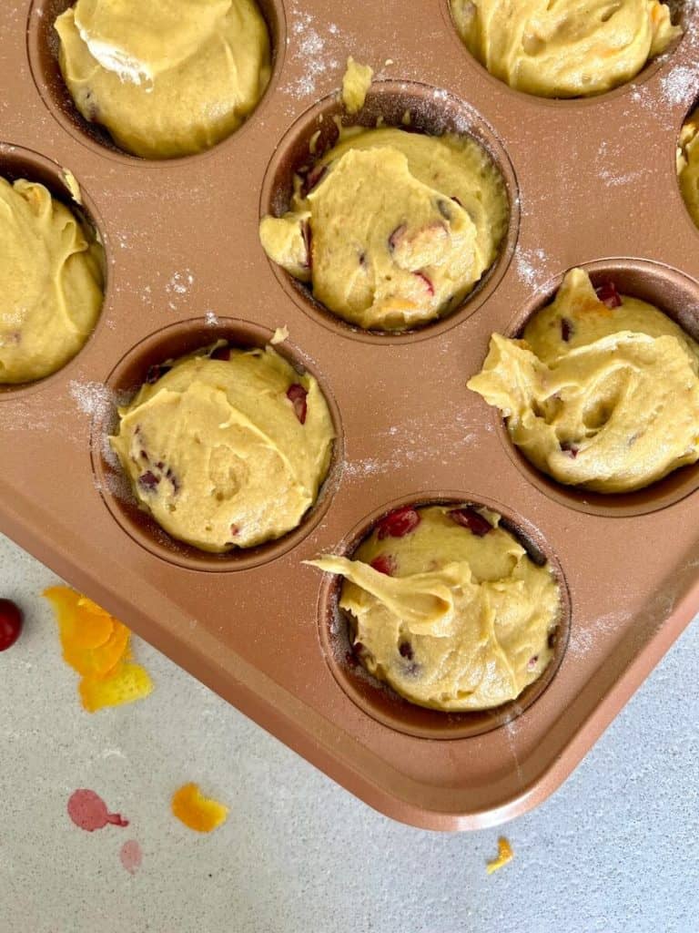 Orange cranberry muffins in a tin.