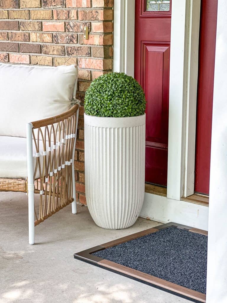 Doormat with a planter pot and outdoor chair.