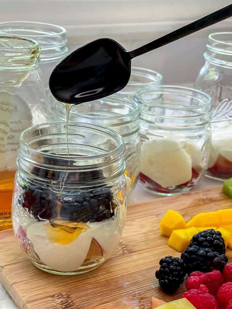 Adding honey to a mason jar.