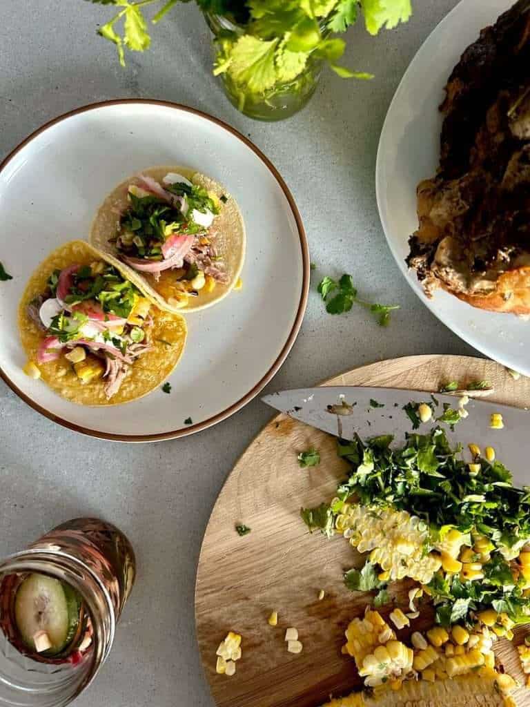 Pulled pork street tacos on a counter with toppings chopped up.