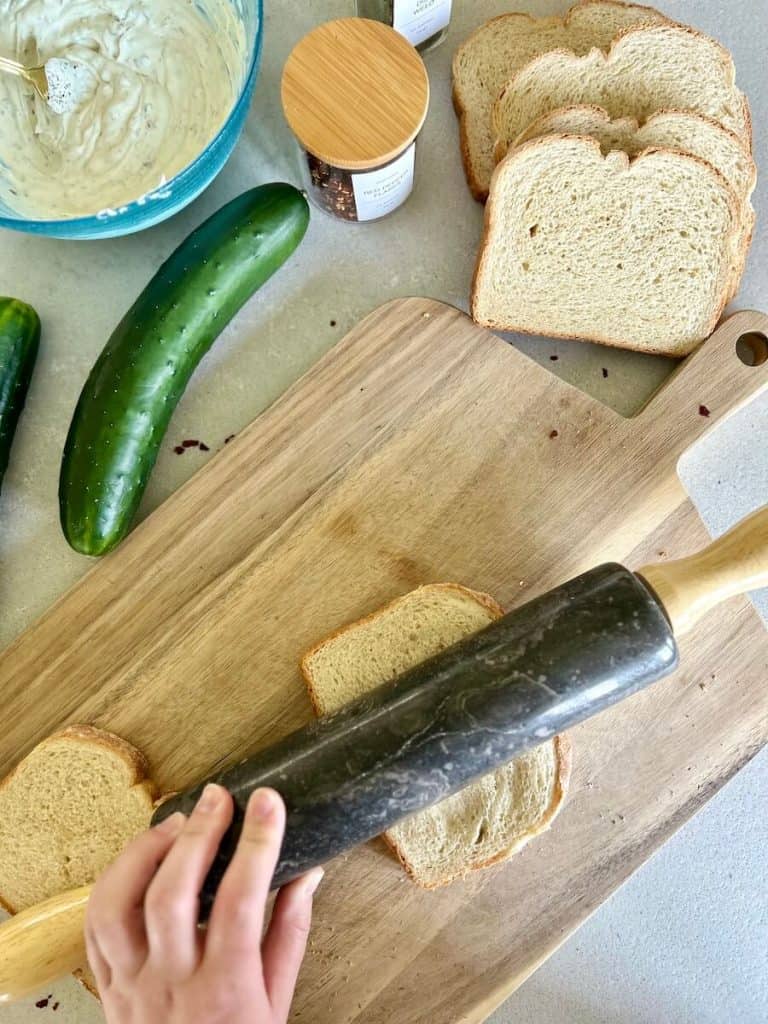 Rolling bread flat for vegan cucumber sandwiches.